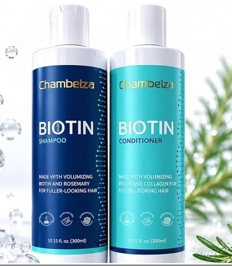 Two Chambelza biotin hair care bottles - dark blue shampoo and turquoise conditioner, each 10.15 fl oz, surrounded by ice cubes and green plant.